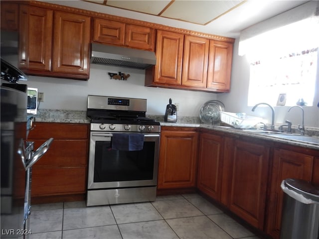 kitchen featuring light tile patterned flooring, stone countertops, stainless steel range oven, and sink