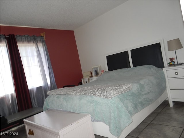 bedroom with a textured ceiling, tile patterned floors, and vaulted ceiling