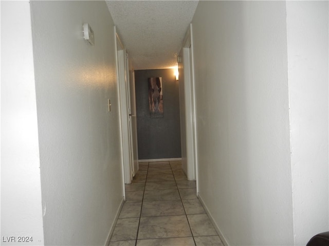 corridor featuring light tile patterned floors and a textured ceiling