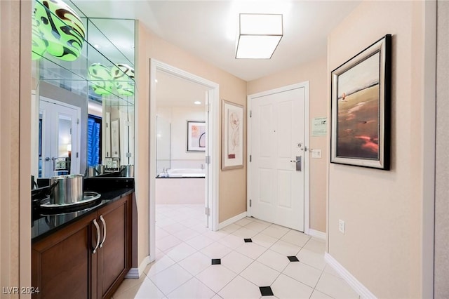 full bathroom with a garden tub, vanity, tile patterned floors, and baseboards