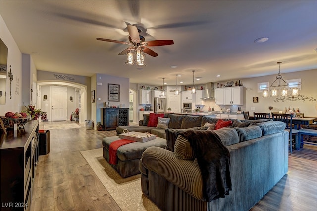 living room featuring light wood-type flooring and ceiling fan with notable chandelier