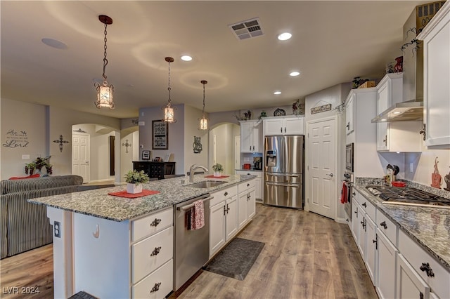 kitchen featuring appliances with stainless steel finishes, white cabinets, a center island with sink, and light hardwood / wood-style floors