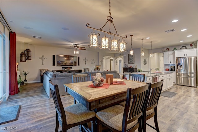 dining area with ceiling fan, sink, and light wood-type flooring