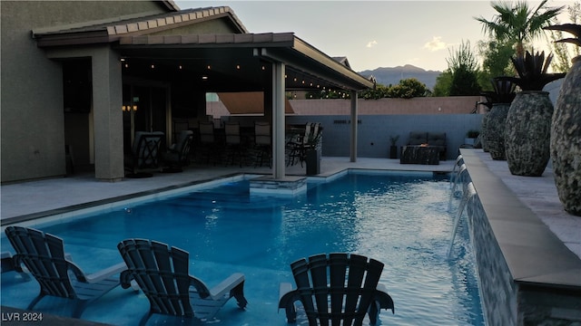 view of swimming pool featuring pool water feature, a mountain view, and a patio area