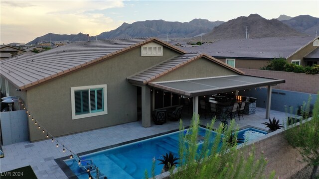 back house at dusk featuring a fenced in pool, a patio, and a mountain view