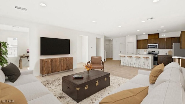 living area with light wood-style flooring, visible vents, and recessed lighting