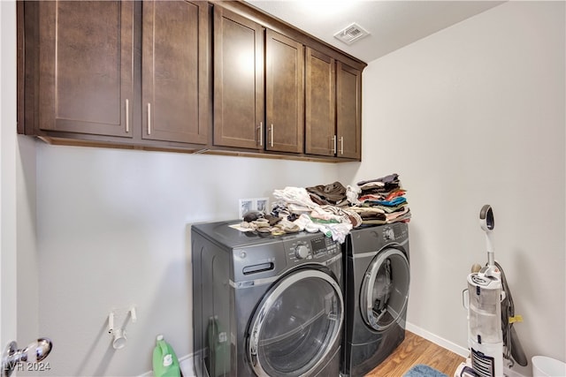 clothes washing area featuring cabinets, light wood-type flooring, and independent washer and dryer