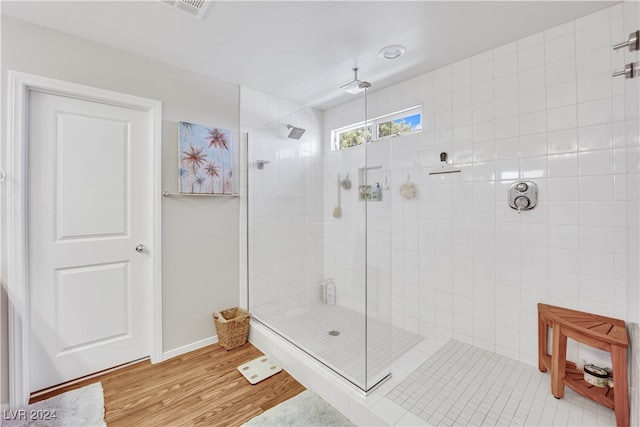 bathroom with tile walls, walk in shower, and hardwood / wood-style floors