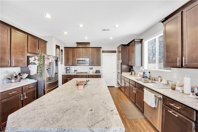 kitchen featuring light stone counters, light wood-type flooring, stainless steel appliances, and a kitchen island