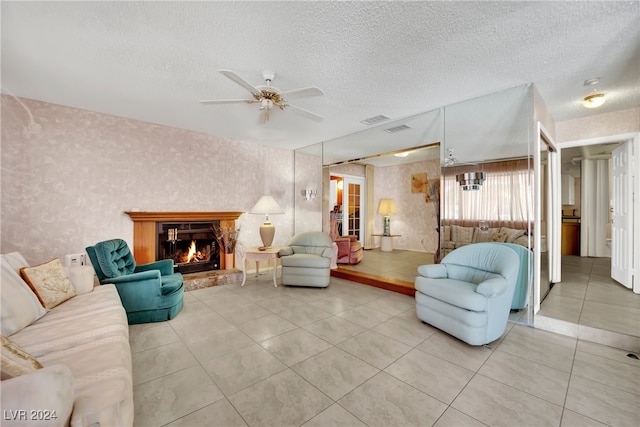 living room with ceiling fan, a textured ceiling, and light tile patterned floors