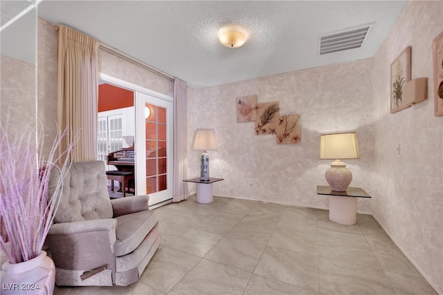 living area with a textured ceiling, french doors, and tile patterned floors