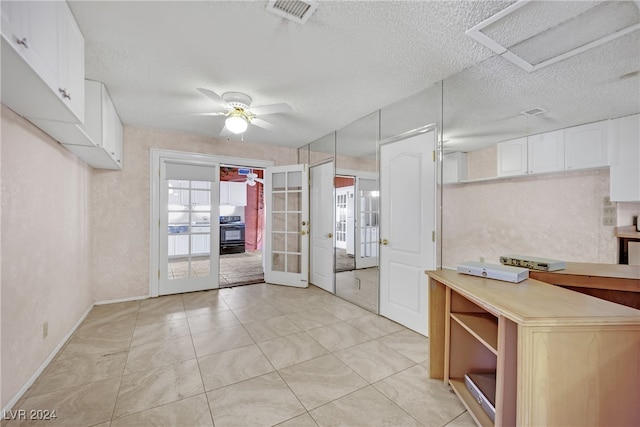 kitchen with stove, white cabinets, ceiling fan, light tile patterned flooring, and french doors