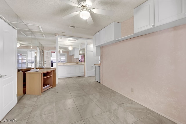 kitchen with a textured ceiling, ceiling fan, white cabinetry, kitchen peninsula, and light tile patterned flooring