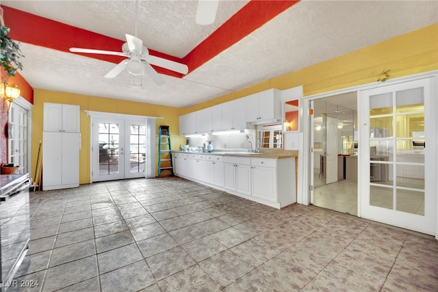 kitchen featuring a textured ceiling, ceiling fan, white cabinetry, french doors, and light tile patterned floors