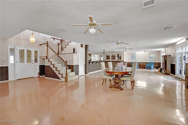 unfurnished dining area with a textured ceiling, french doors, tile patterned floors, and ceiling fan