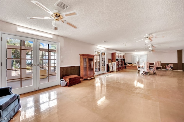 living room featuring ceiling fan, french doors, and a textured ceiling