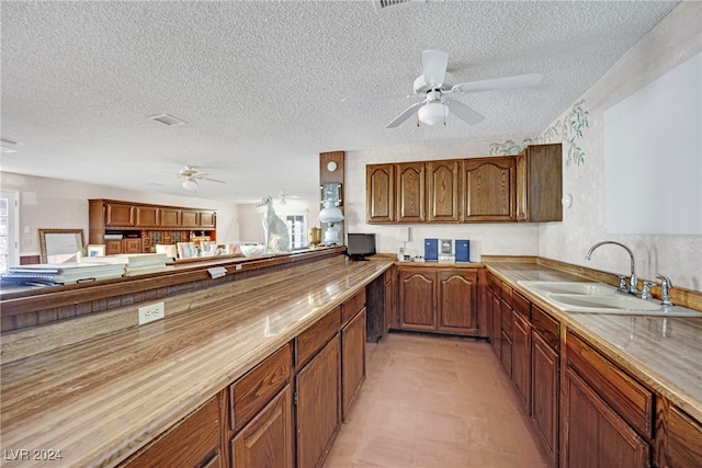 kitchen with ceiling fan, sink, a textured ceiling, and light tile patterned floors