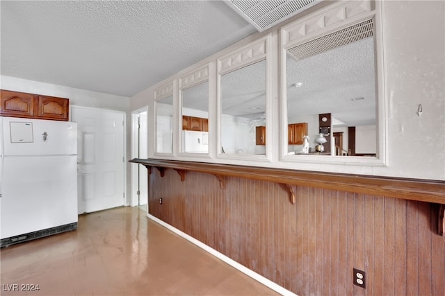 kitchen featuring white refrigerator, a textured ceiling, a breakfast bar, and kitchen peninsula