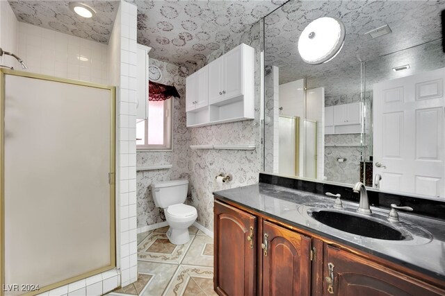 bathroom featuring vanity, a shower with door, toilet, and tile patterned flooring