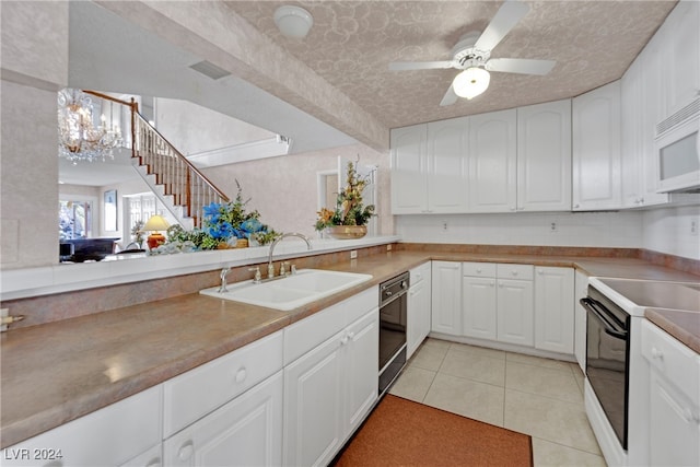 kitchen featuring white appliances, ceiling fan with notable chandelier, white cabinetry, light tile patterned floors, and sink