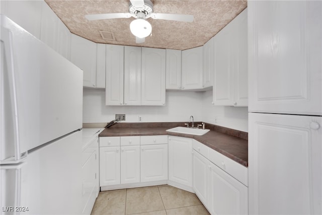 kitchen with light tile patterned floors, white cabinets, ceiling fan, sink, and white fridge