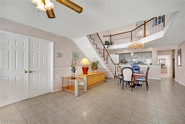 tiled dining area with ceiling fan with notable chandelier and a textured ceiling