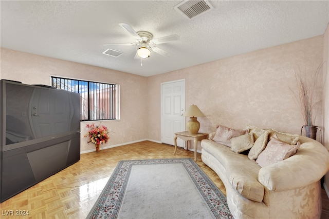 living room featuring ceiling fan, a textured ceiling, and light parquet flooring