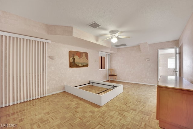 interior space with a textured ceiling, parquet flooring, and ceiling fan