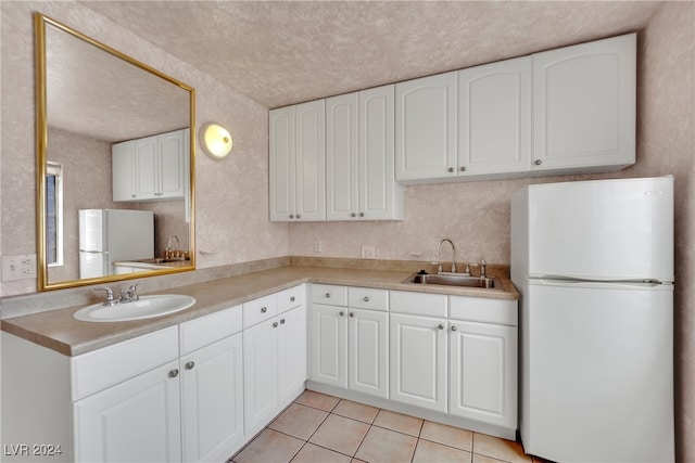 kitchen with white cabinetry, sink, and white fridge