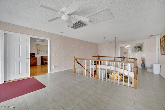 unfurnished room featuring light tile patterned flooring, a textured ceiling, and ceiling fan