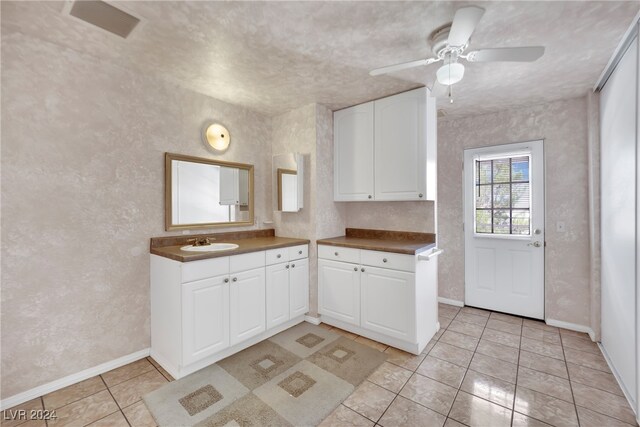 kitchen featuring light tile patterned floors, sink, ceiling fan, and white cabinetry