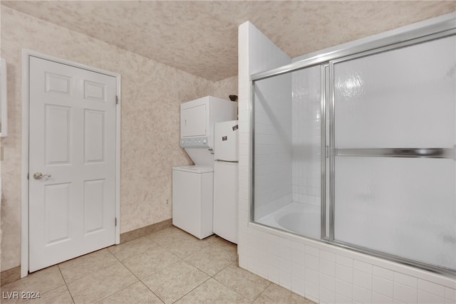 bathroom featuring shower / bath combination with glass door, stacked washer and dryer, and tile patterned flooring