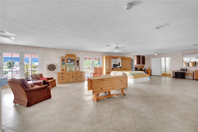 tiled living room featuring ceiling fan, a textured ceiling, and plenty of natural light