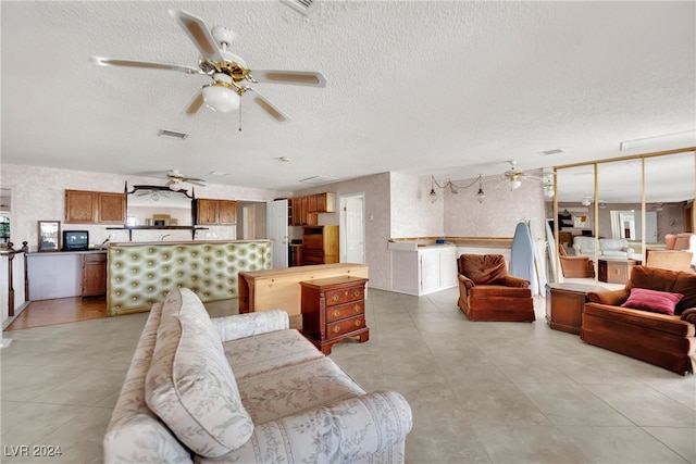 living room with light tile patterned flooring, a textured ceiling, and ceiling fan