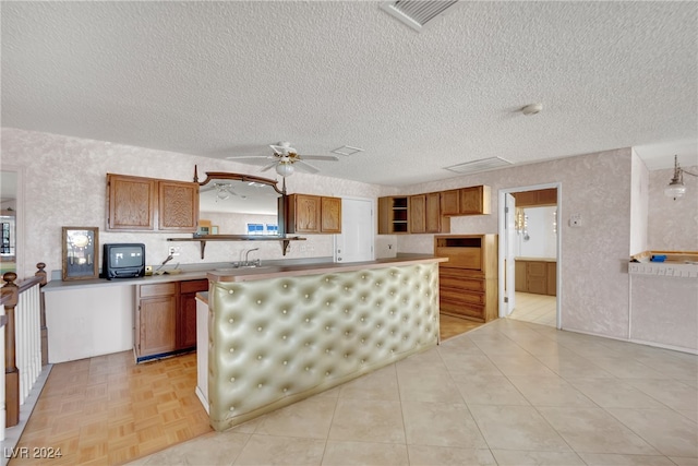 kitchen with wall oven, ceiling fan, a textured ceiling, and light parquet floors