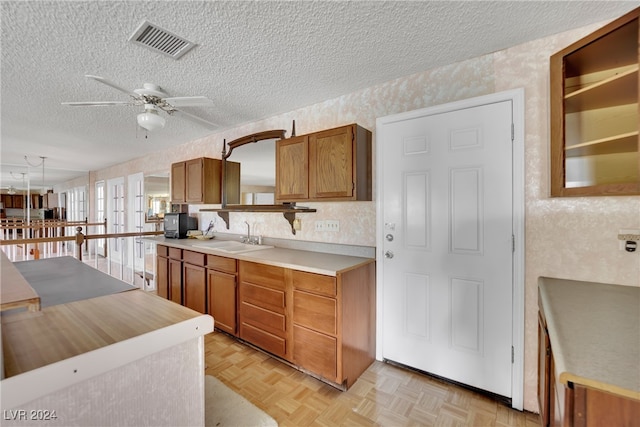 kitchen featuring a textured ceiling, light parquet flooring, sink, and ceiling fan