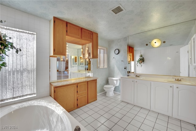 bathroom featuring double sink vanity, a bathing tub, tile patterned floors, and toilet