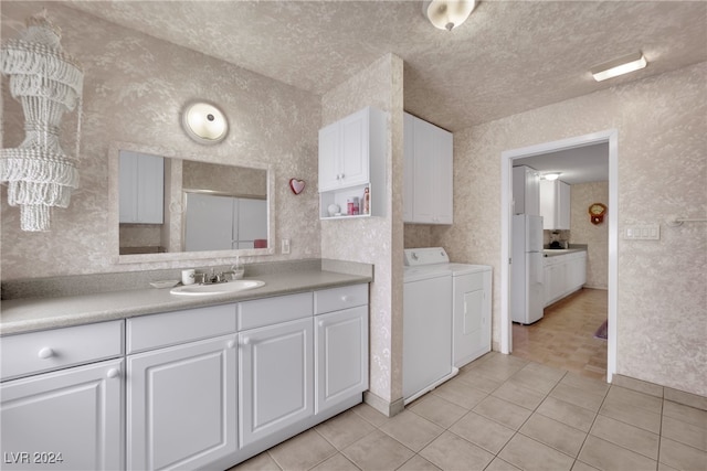 kitchen featuring light tile patterned floors, washer and dryer, white refrigerator, white cabinets, and sink