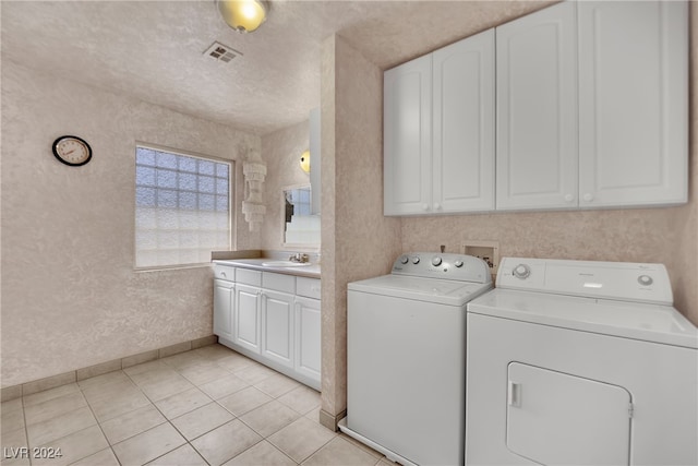 laundry area featuring a textured ceiling, washer and dryer, cabinets, light tile patterned floors, and sink