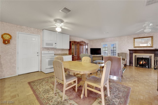 dining space featuring ceiling fan, french doors, a high end fireplace, and light parquet flooring