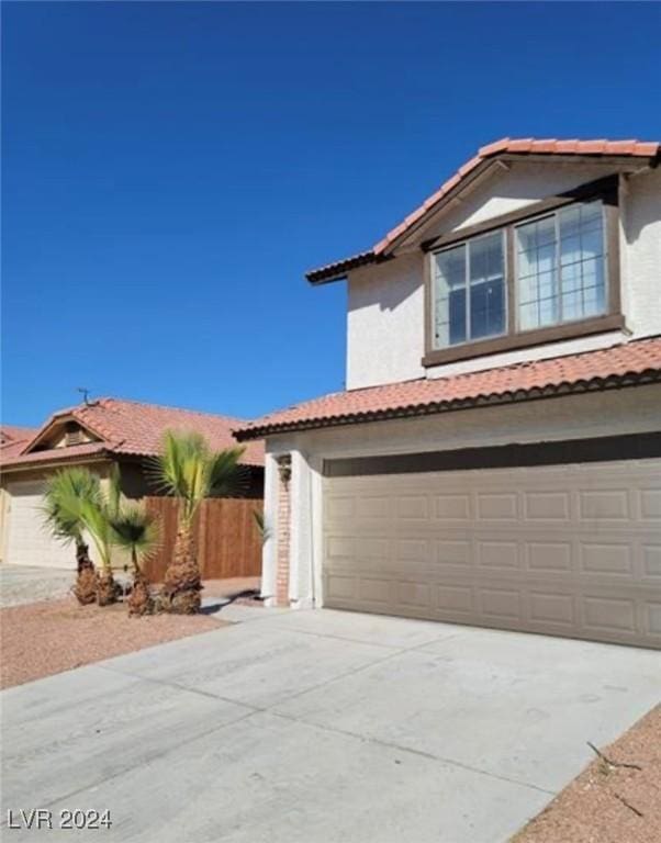 6444 Deadwood Rd, Las Vegas, NV 89108 - view of front of house with fence, driveway, an attached garage, stucco siding, and a tile roof