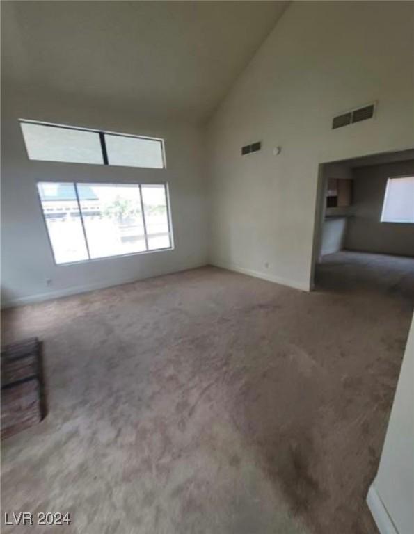 unfurnished living room featuring high vaulted ceiling and carpet flooring