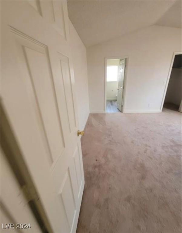 carpeted spare room with lofted ceiling