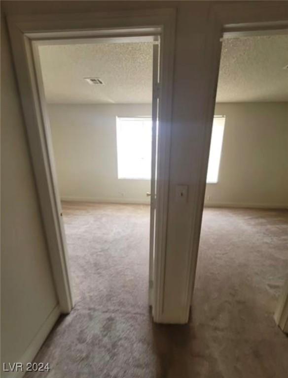 corridor with a textured ceiling and carpet