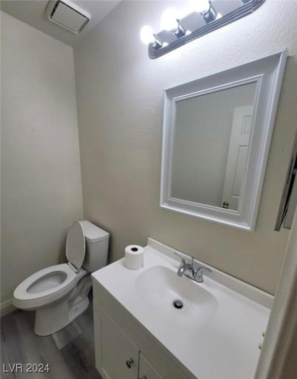 bathroom with hardwood / wood-style floors, vanity, and toilet