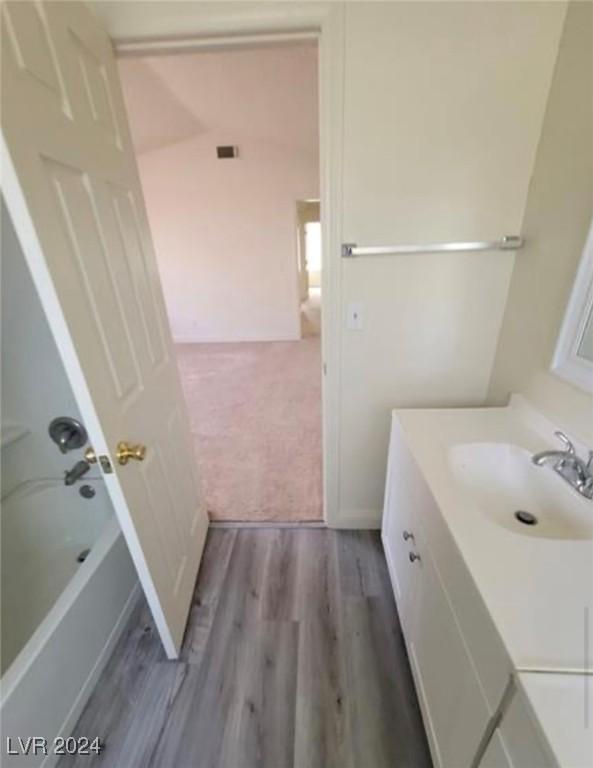 bathroom featuring vanity, wood-type flooring, and shower / washtub combination