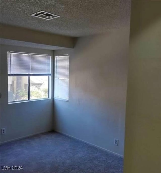 carpeted empty room featuring a textured ceiling