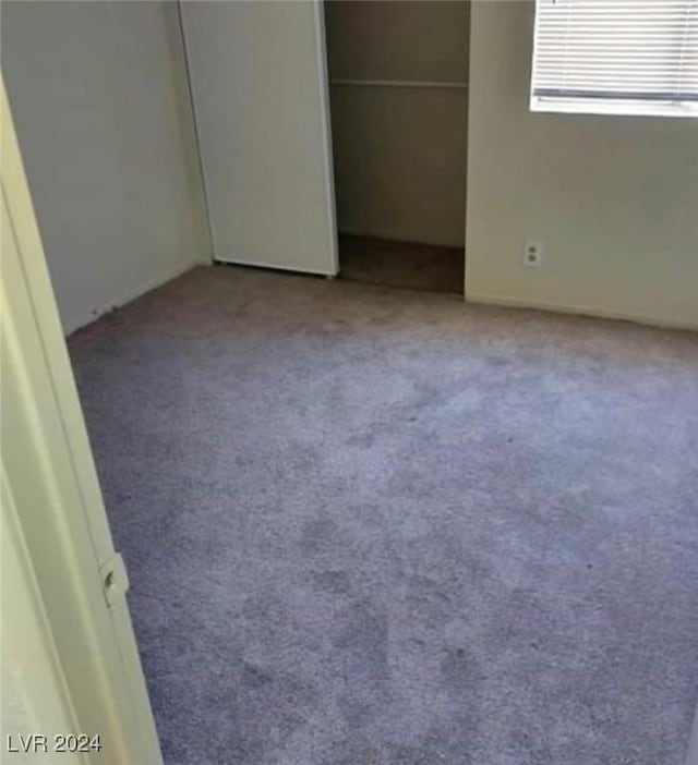 unfurnished bedroom with light colored carpet and a closet