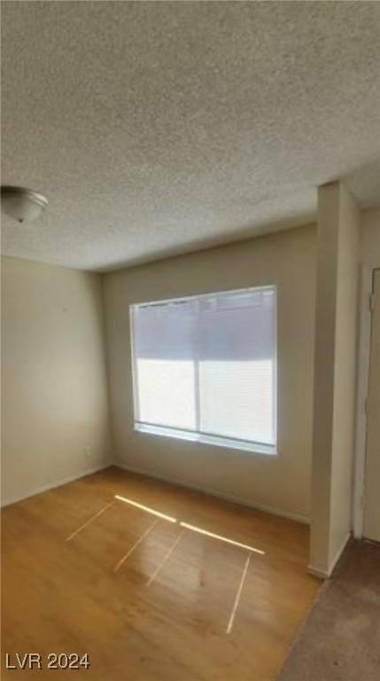 unfurnished room featuring hardwood / wood-style flooring and a textured ceiling