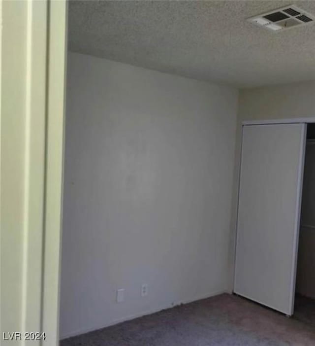 empty room with carpet and a textured ceiling